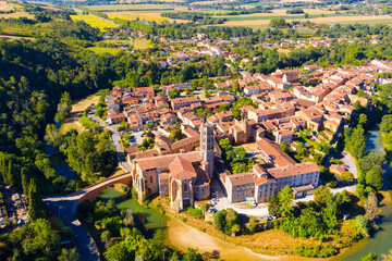 View from drone of houses and ancient Roman Catholic Cathedral of Rieux-Volvestre town at sunny summer day, France