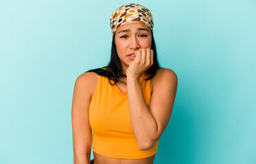 Young Venezuelan woman isolated on blue background biting fingernails, nervous and very anxious.