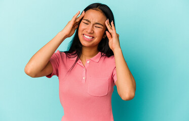 Young Venezuelan woman isolated on blue background touching temples and having headache.
