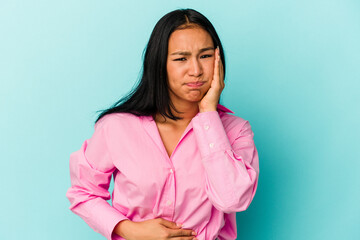 Fototapeta premium Young Venezuelan woman isolated on blue background blows cheeks, has tired expression. Facial expression concept.