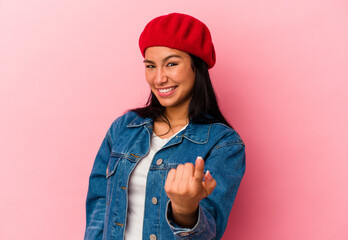 Young Venezuelan woman isolated on pink background pointing with finger at you as if inviting come closer.