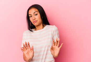 Young Venezuelan woman isolated on pink background rejecting someone showing a gesture of disgust.