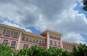 Fototapeta na wymiar Classical building of an old public school downtown Madrid, Spain. Voluminous cloudscape