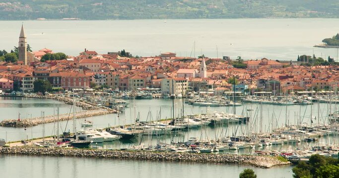 Elevated view of old town Izola in Slovenia. Adriatic sea coast. Boats and yachts docket in marina. Panoramic static shot of Mediterranean settlement Isola on bright sunny day