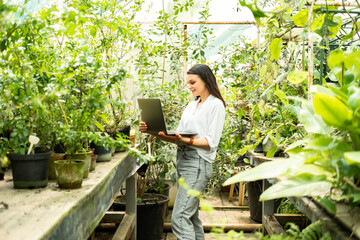 attractive business women gardener using laptop. Modern technology in gardening business.