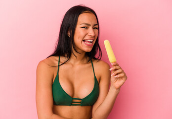 Young Venezuelan woman holding an ice cream isolated on pink background