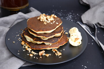 Banana pancakes and walnut crumbs on a black background.
