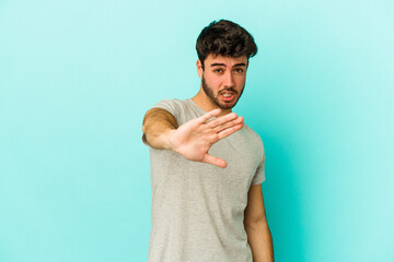 Young caucasian man isolated on blue background rejecting someone showing a gesture of disgust.