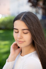 Obraz premium close-up of a young brunette girl who looks down on background of green grass