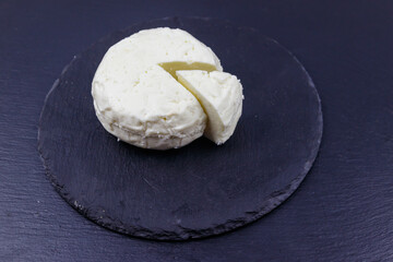 Soft Adyghe cheese on black slate background