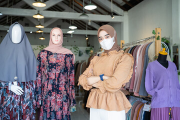 close up of a woman in a veil wearing a mask and crossing her arms stands inside a boutique shop