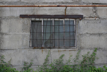 an old window with a metal grate on a gray cinder block wall