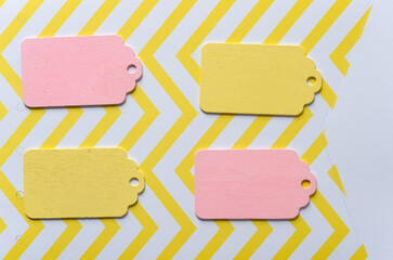 four wooden pastel yellow and baby pink chalkboard tags on a yellow and white zig zag paper...