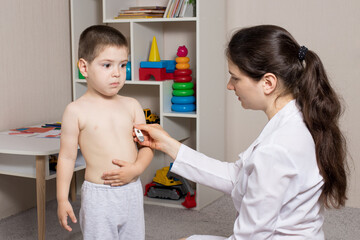 A pediatrician or nurse measures a child body temperature with a thermometer. Fever in children,...