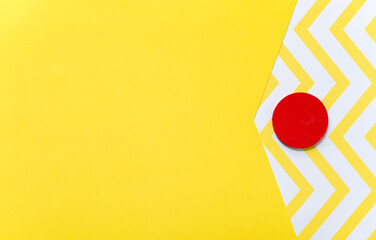 solid and patterned yellow and white paper background with a hand painted red wooden disc
