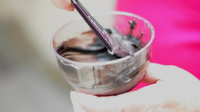 Mixing hair dye bowl and brush paint dark paint and bowl in women's hands