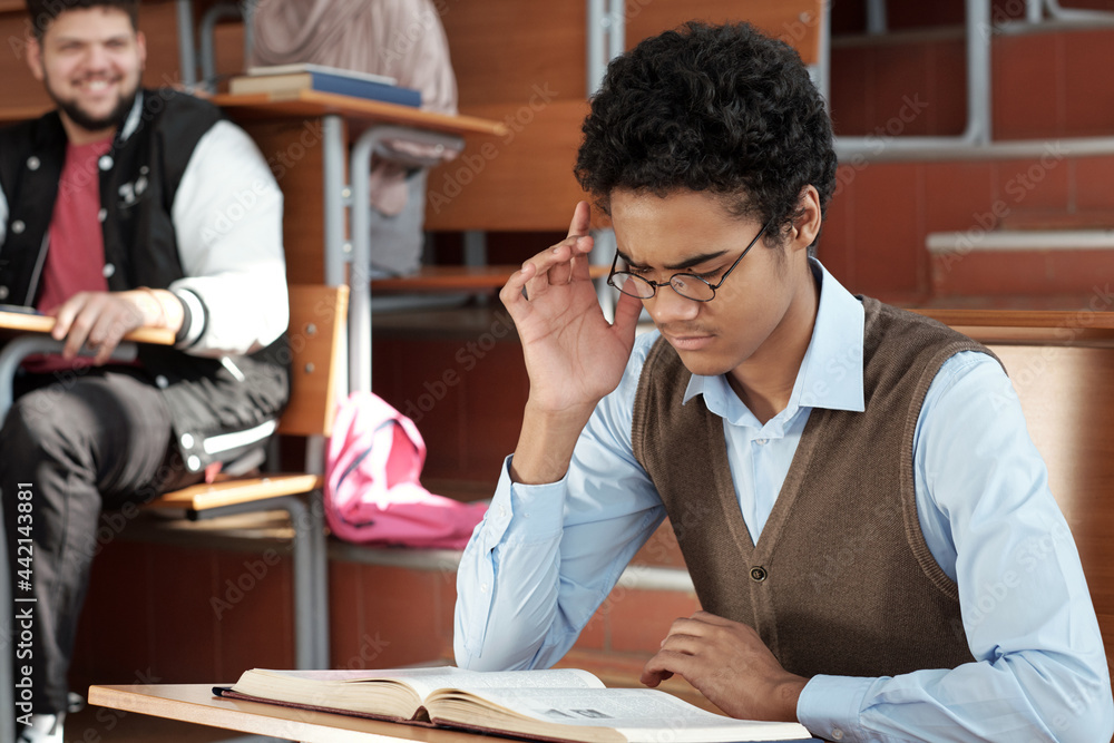 Poster mixed-race guy trying to concentrate while reading book at lesson