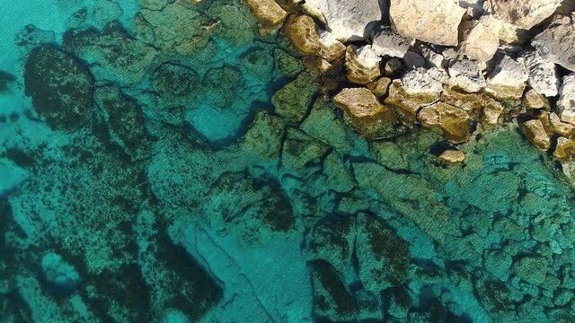 Aerial top view 4k footage by drone of ocean blue water and rocks, A calm sea washes the rocky mountain, Edge of the World and the blue sea beach, Dramatic geological wonder, Beautiful landscape