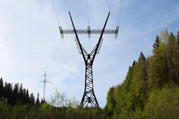 A large metal pole of a power line in the forest. Close-up. Background. Scenery.