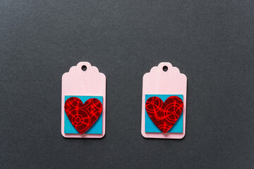 two, isolated wooden pastel pink chalkboard tags on a dark gray paper background featuring two iridescent hearts on blue squares