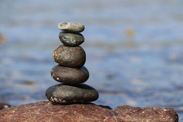Fototapeta na wymiar Tower of pebble stones on a sea beach. Zen balance, tranquility concept