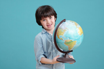 Adorable schoolboy or preschooler with globe looking at you