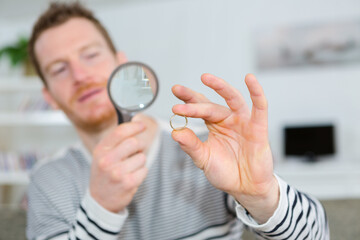 midsection of businessman examining ring with magnifying glass