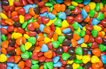 Chocolate candies of bright colors in the shape of hearts. Fruits nuts vegetables berries useful products agriculture.