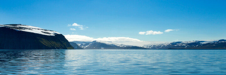 Beautiful mountains with snow picks and turquoise water of Atlantic ocean. Westfjords, Iceland. Horizontal banner.