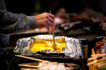 Closeup of tamagoyaki Japanese eggs rolled omelet on retail display in Kyoto, Japan Nishiki market street with person serving portion of omelette