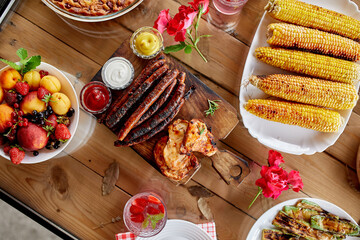 Dinner table with meat grill, roast vegetables, sauces and lemonade, appetizers variety serving on party outdoor table..