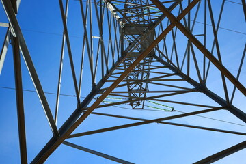 Power transmission tower close-up. Geometric, silhouette. Blue sky at the background.