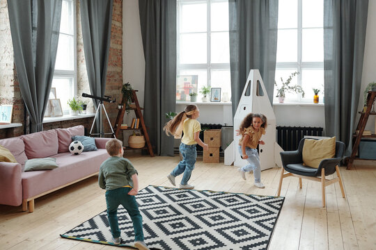 Three happy kids playing catch-up in living-room
