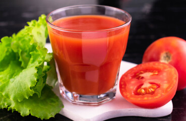 A glass of tomato juice on a black background.
Close-up.