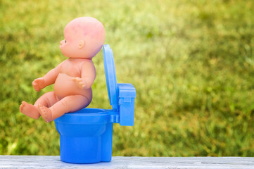 baby doll Sitting On A Potty. teaching child to potty train. Concept for the child doesn't want on...