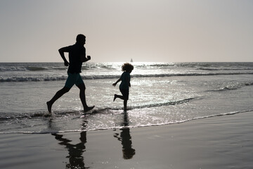 Fototapeta premium daddy with kid boy silhouette in sea or ocean. weekend family day. dad and child having fun