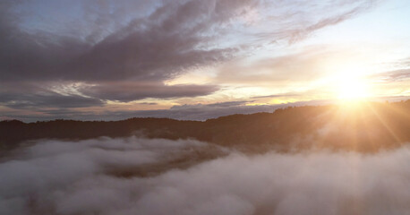 Flying over the evening time clouds with the late sun. Flight through moving cloudscape with beautiful sun rays. Traveling by air. Perfect for cinema, background