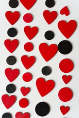 Fototapeta na wymiar black and red wooden shapes arranged in columns on a light background or dots and hearts