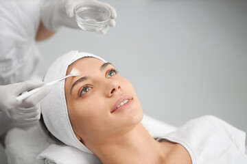 Side view of smiling young cute woman on procedure for improvements face skin. Concept of beauty...