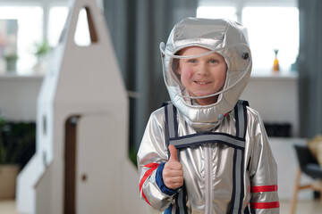 Cheerful little boy in space-suit showing thumb-up © pressmaster