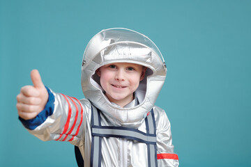 Cheerful boy in space-suit keeping thumb up and looking at you