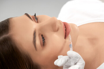 Side view of young attractive woman procedure for lip augmentation in professional salon. Concept...