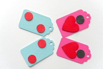 pastel colored wood chalkboard tags loosely arranged in a classic arragement with hand painted red hearts and black discs on a white paper background