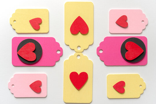 pastel colored wood chalkboard tags loosely arranged in a classic arragement with hand painted red hearts and black discs on a white paper background