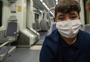 Fototapeta na wymiar View of a boy wearing a mask inside a subway car in Malaga during pandemic.
