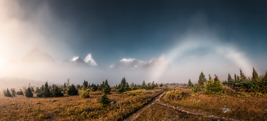 Scenery of foggy mount Assiniboine with fog bow phenomenon in autumn forest at provincial park