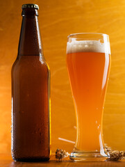 A tall glass of a pint of beer on a wooden table, a beer bottle. Unfiltered traditional wheat beer