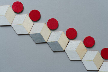 low-key photo with trompe l'oeil cubes and red discs arranged on a gray paper background