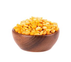 Dry yellow split peas in wooden bowl, isolated on white background. Halves of yellow legume peas.