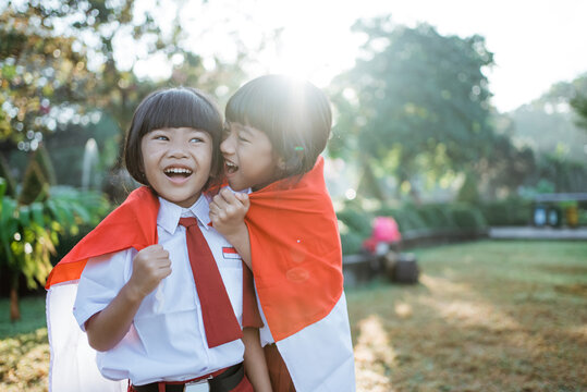 two indonesian school student holding flag during independence day. proud primary pupil with indonesia flag outdoor
